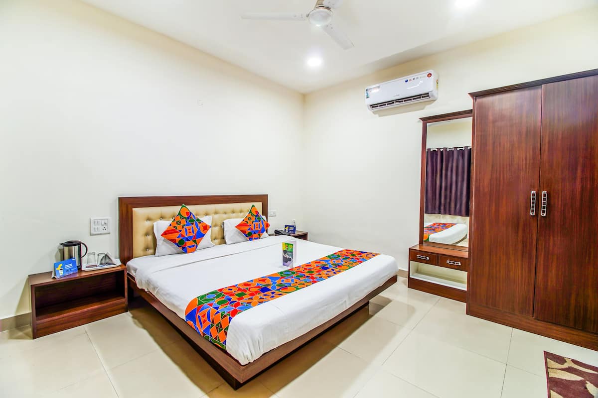A hotel room with a bed, nightstand, wardrobe, and an air conditioning unit.