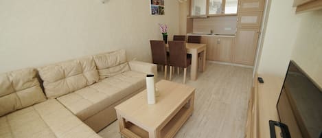 A modern living room with a beige sofa, a wooden coffee table, and a TV on a stand.