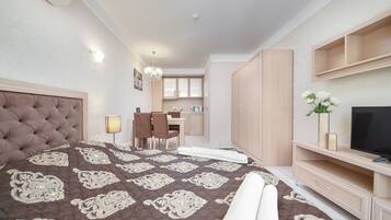 A bedroom with a large bed, a desk, and a TV.