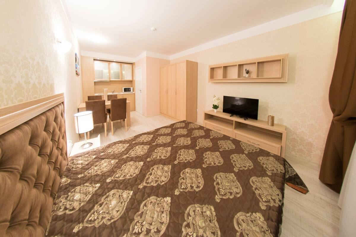 Un dormitorio con una cama grande, televisión, escritorio y armario.