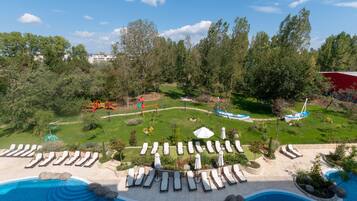 Un espace piscine avec des chaises longues et un petit jardin.