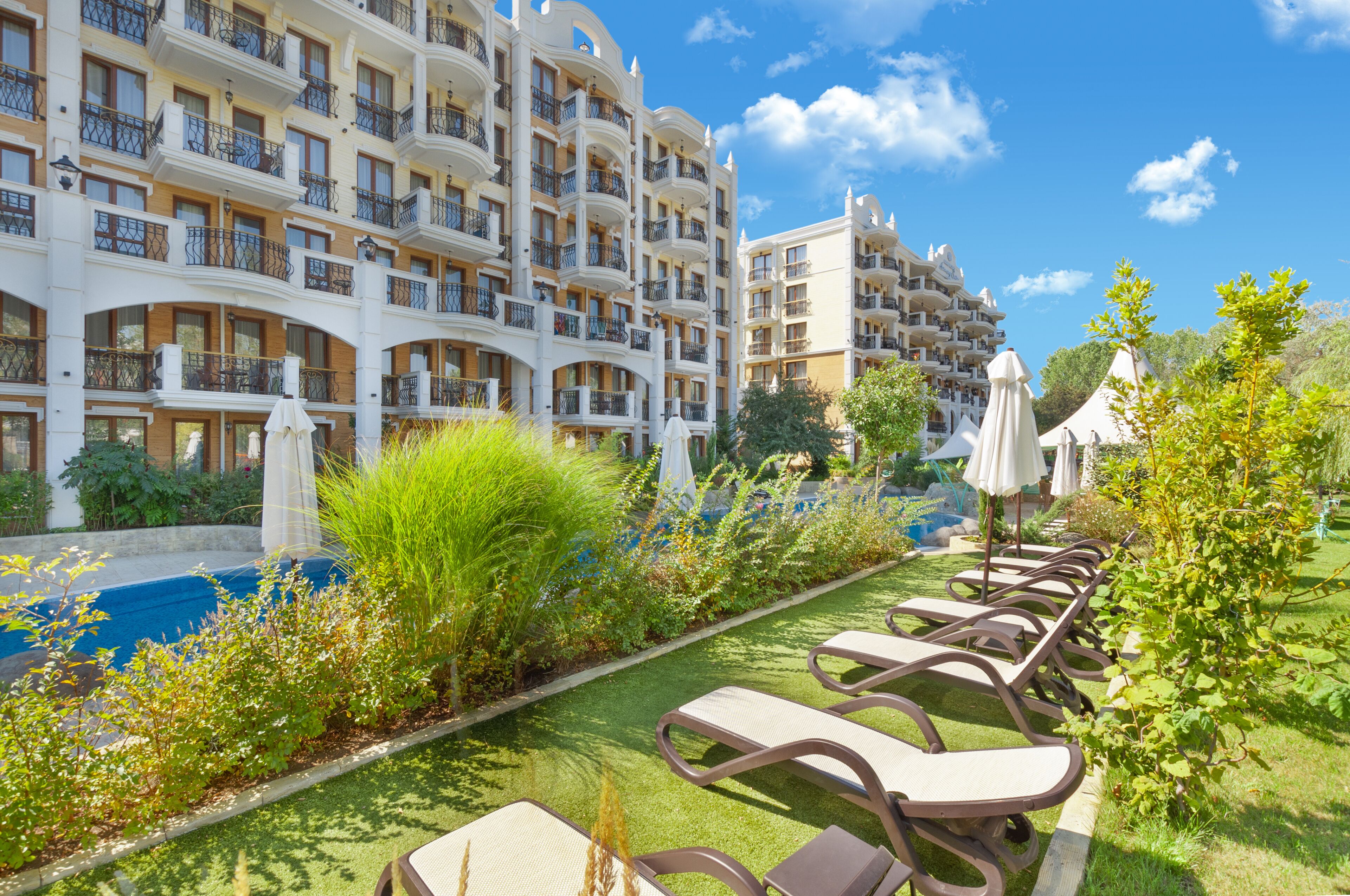 Un hotel con varios balcones, piscina y sillones de exterior.