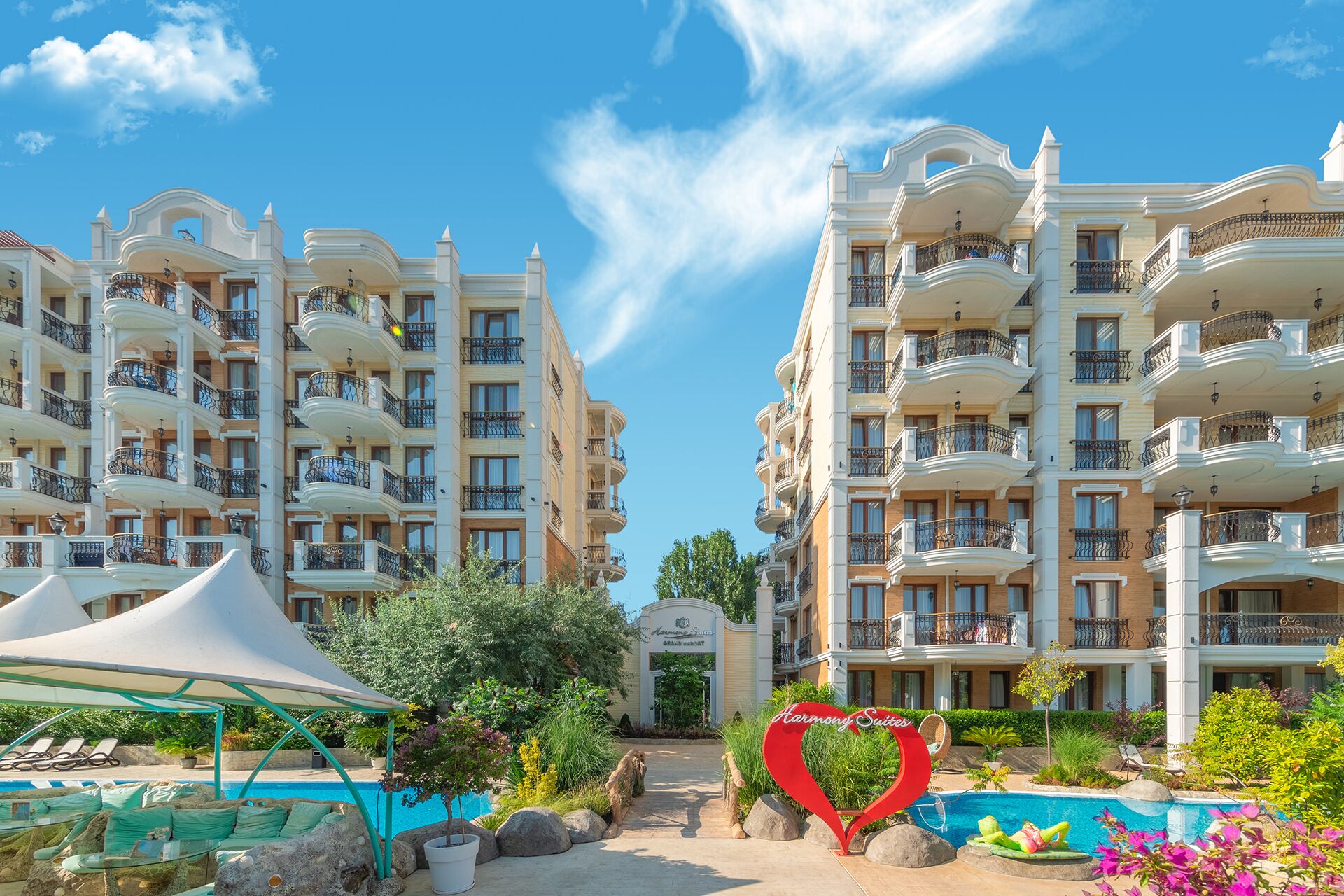 Un hôtel doté de nombreux balcons, d’une piscine et d’un panneau en forme de cœur.