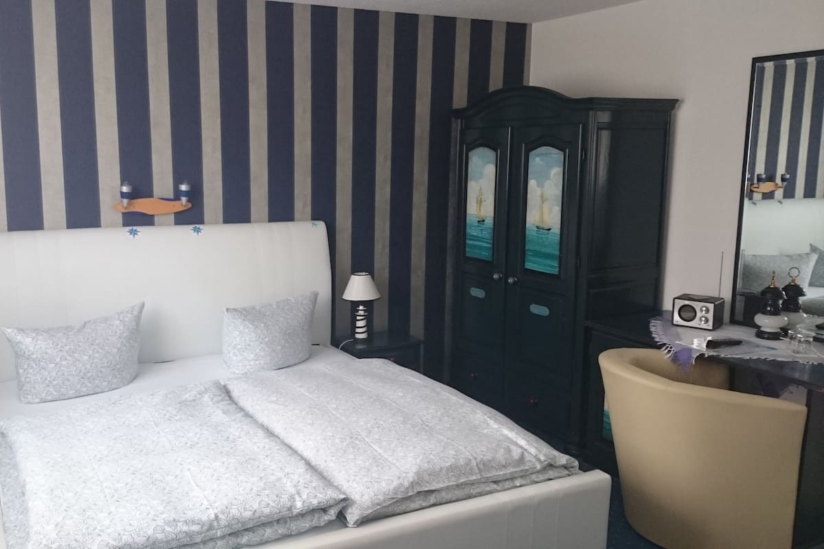 Una habitación de hotel con cama, cómoda, escritorio y espejo.