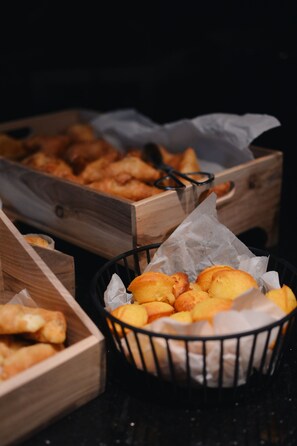 Wooden crates filled with baked goods, including bread and pastries, on a dark surface. - Hotel Mona Plaza (Belgrade)