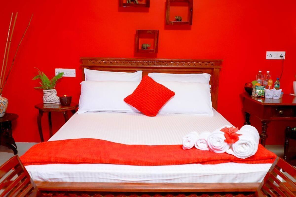 Un lit avec du linge de lit blanc, un oreiller rouge et une couverture rouge. Deux petits tableaux encadrés sont accrochés au mur au-dessus du lit.