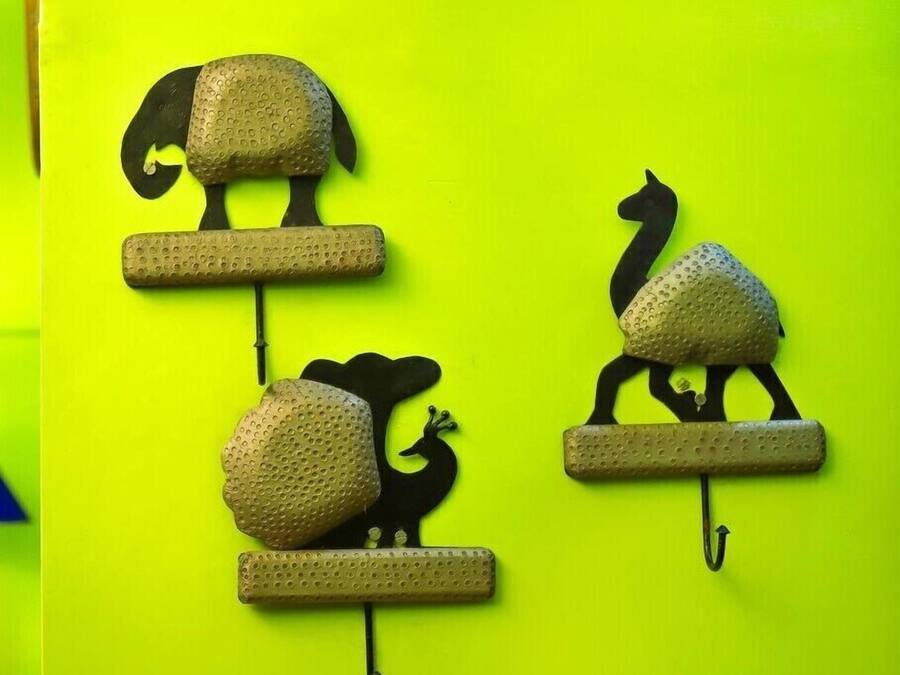 Drei an der Wand befestigte Tier-Skulpturen, jede mit einer strukturierten Oberfläche und einer flachen Basis, vor einem leuchtend gelben Hintergrund.