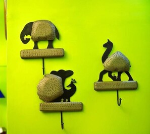 Drie dierenbeeldjes aan de muur bevestigd, elk met een reliëfachtig oppervlak en een platte basis, voor een heldergele achtergrond.