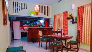 Un área de comedor con una mesa y sillas de madera, una cocina al fondo y adornos en la pared.
