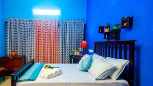 Un dormitorio con cama, mesita de noche, lámpara y estante en la pared con objetos decorativos.