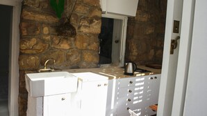 Una cocina con pared de piedra, dos fregaderos, una ventana y armarios.