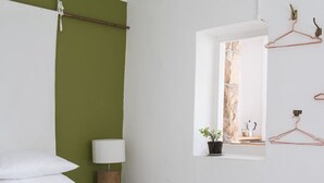 Un dormitorio con cama, mesita de noche, ventana con vistas y espejo adosado a la pared.