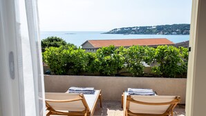 A balcony with two wooden chairs and a table, overlooking a coastal view with greenery and buildings. - Newly renovated townhouse  w/ garden and sea-view for 4 guests in old Antibes (Antibes)