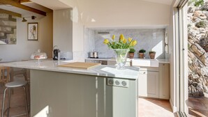A modern kitchen with a marble backsplash, a central island with a glass cover, and a view of a stone wall outside. - Newly renovated townhouse  w/ garden and sea-view for 4 guests in old Antibes (Antibes)