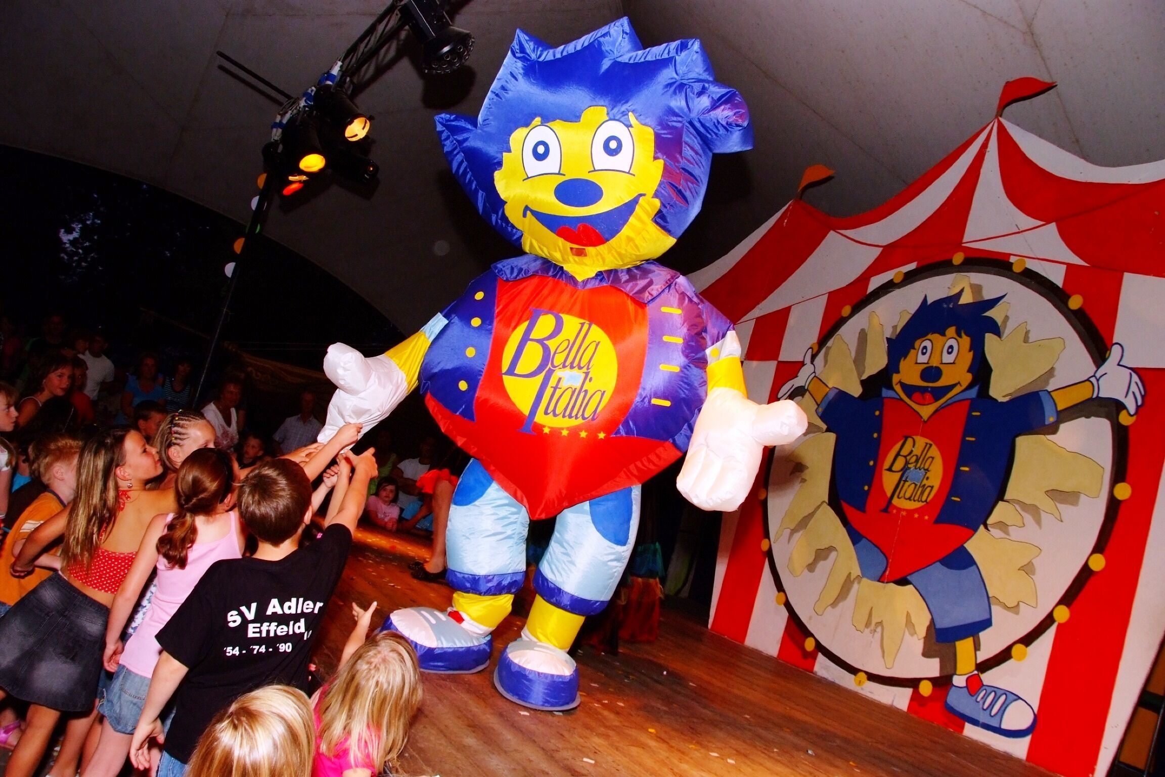 A large inflatable character on a stage with a crowd of people in the background.