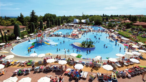 A large outdoor swimming pool with multiple lanes, surrounded by sun loungers and umbrellas. - Happy Camp in Camping Bella Italia (Peschiera del Garda)