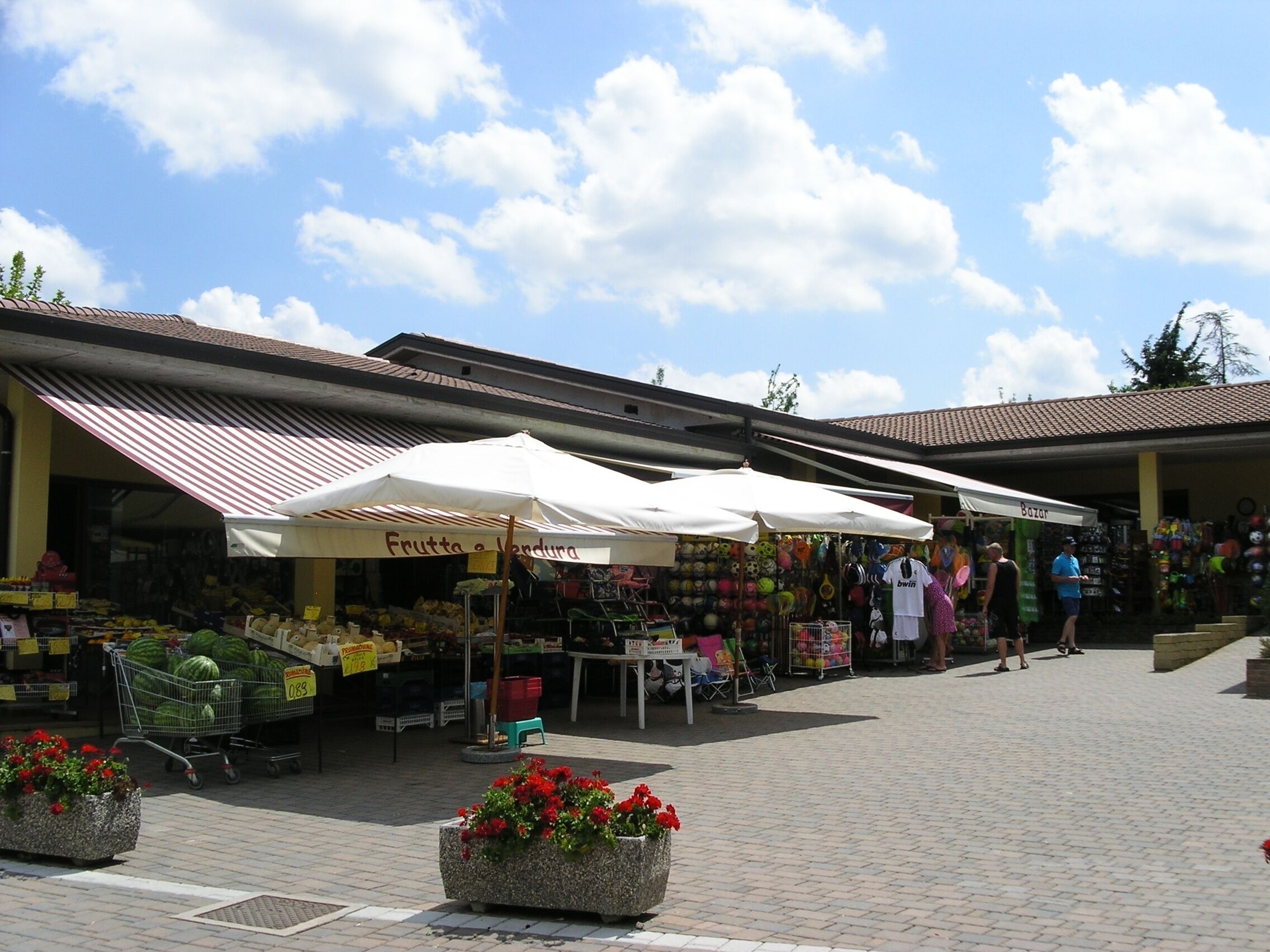 An outdoor market with various stalls, including one selling fruits and vegetables.
