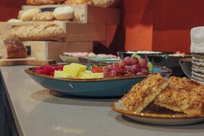 A buffet with various food items including fruits, pastries, and bread. - YEBO Boutique Guesthouse (Cape Town)