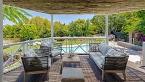Un espace extérieur aménagé avec des meubles en osier, une piscine et une végétation luxuriante en arrière-plan.