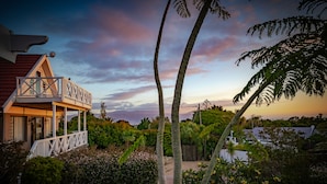 Une maison avec un balcon donnant sur un jardin et offrant une vue sur le ciel.