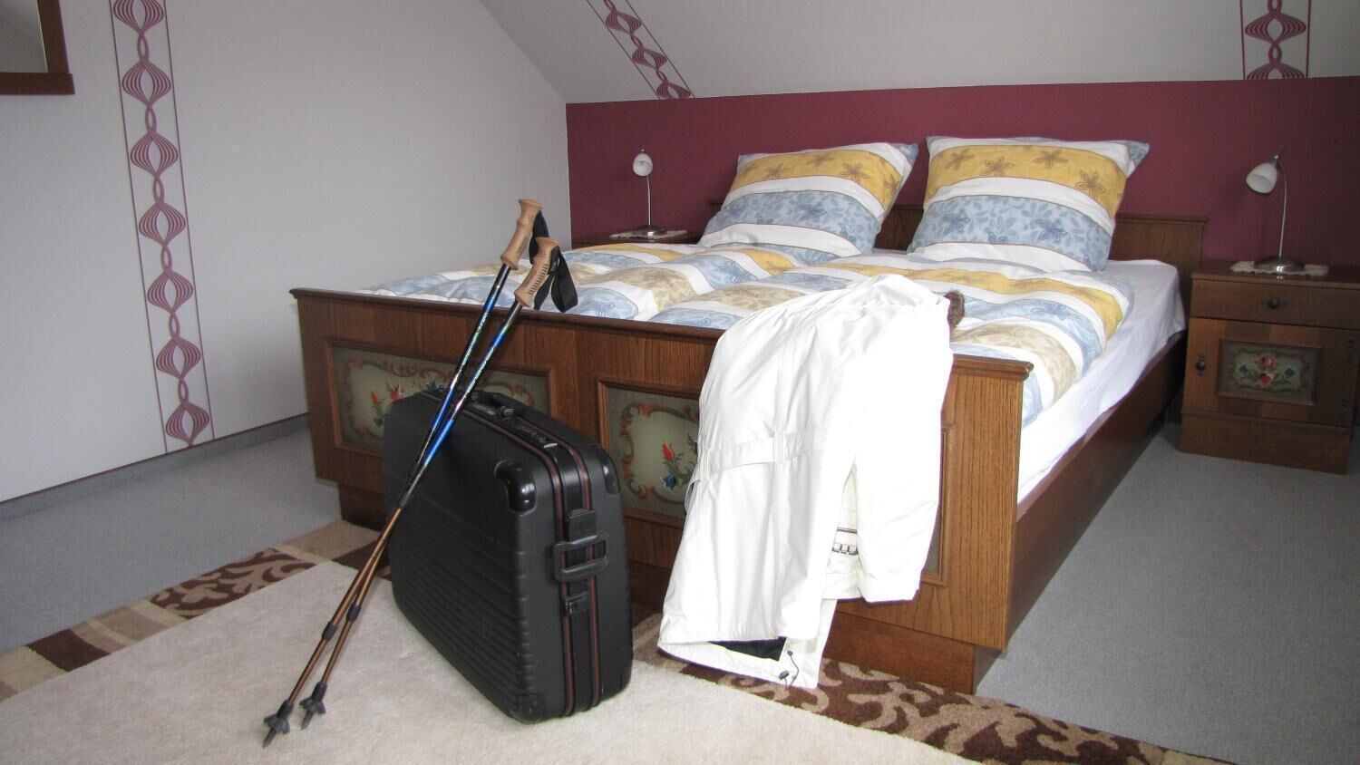 A bedroom with a bed, a suitcase, and a coat on the floor.