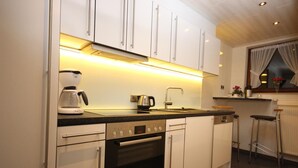 Una cocina moderna con gabinetes blancos, un horno Bosch, una cafetera y un lavamanos.