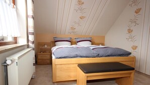 Un dormitorio con cama de madera, una mesita de noche, una lámpara y un radiador.