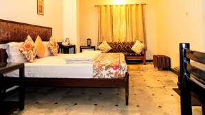Una habitación de hotel con cama, sofá, una mesita y una silla.
