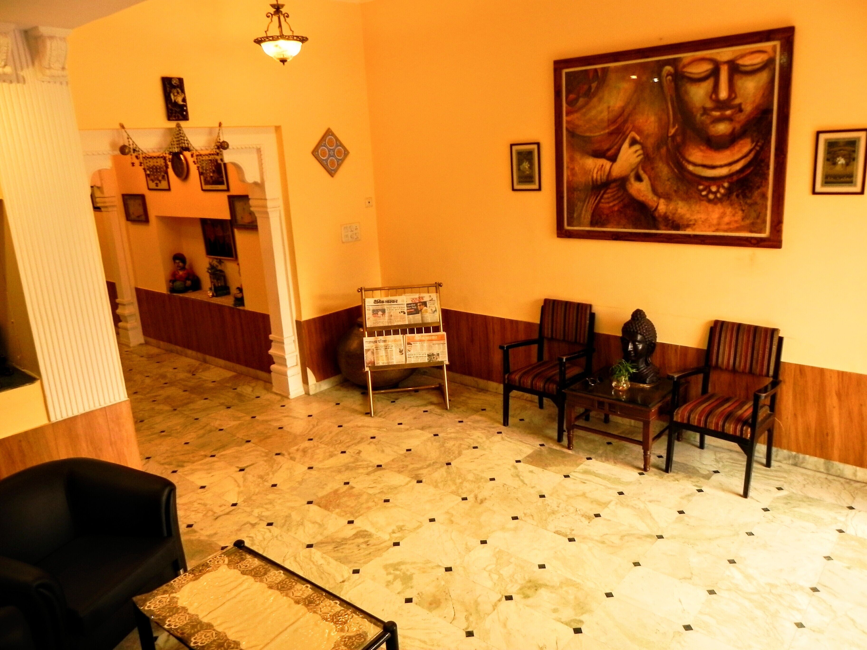 Zona de recepción con una estatua de Buda, un mostrador de recepción y varias sillas.