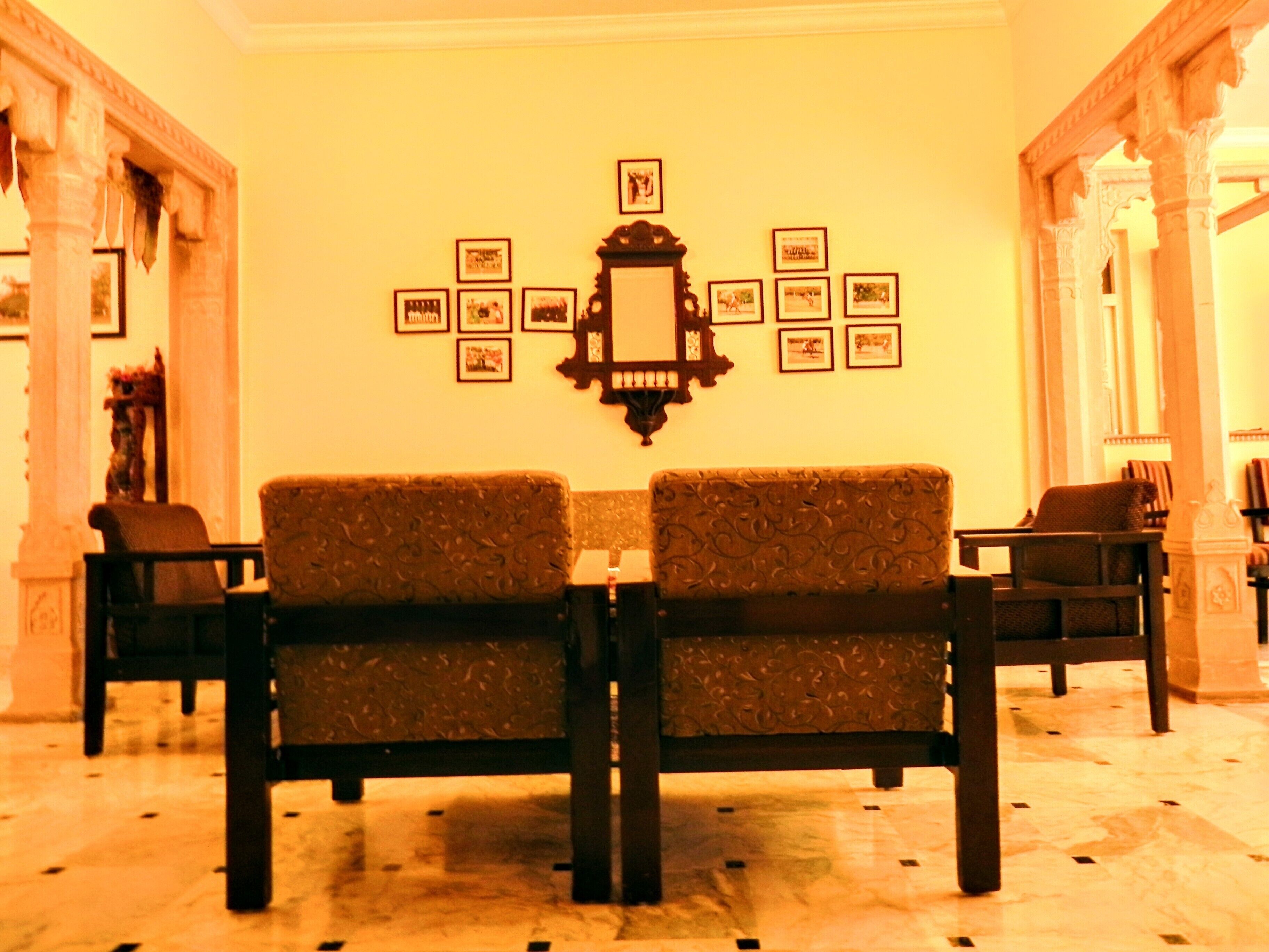 A lobby with a sofa set, framed pictures on the wall, and classical architecture.
