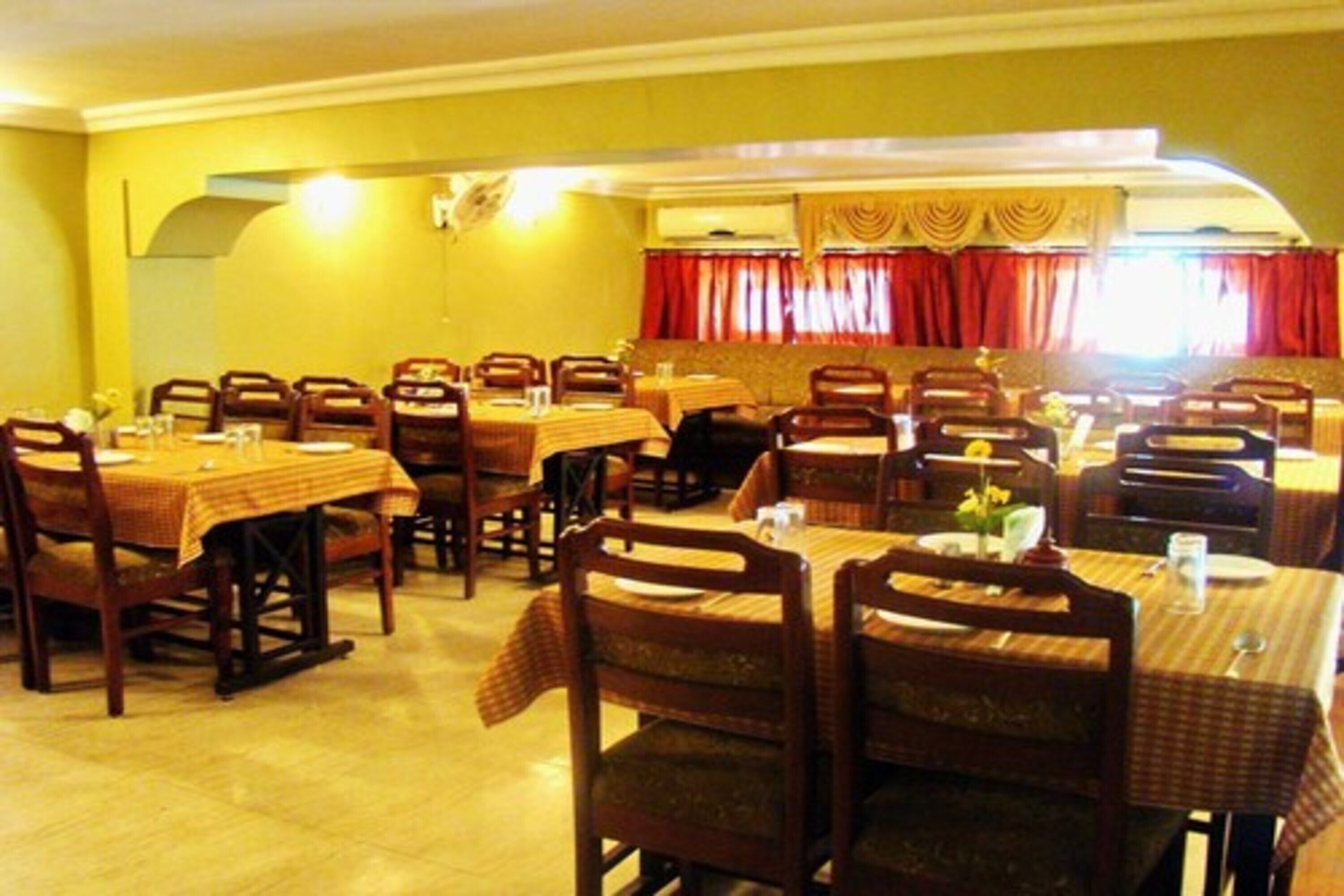 Restaurante com várias mesas e cadeiras de madeira, dispostas numa configuração ampla.