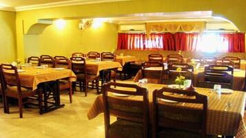 Restaurante com várias mesas e cadeiras de madeira, dispostas numa configuração ampla.