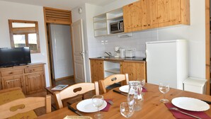 Una cucina compatta con mobili in legno, un forno a microonde, una macchina da caffè e un frigorifero.