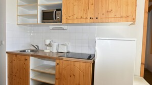 Una cucina con mobili in legno, un forno a microonde, una macchina per il caffè, un tostapane e un frigorifero.