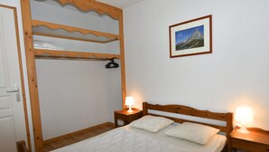 Una camera da letto con un letto a castello, un letto singolo, una testiera in legno, comodini con lampade e un quadro appeso al muro, più una porta.