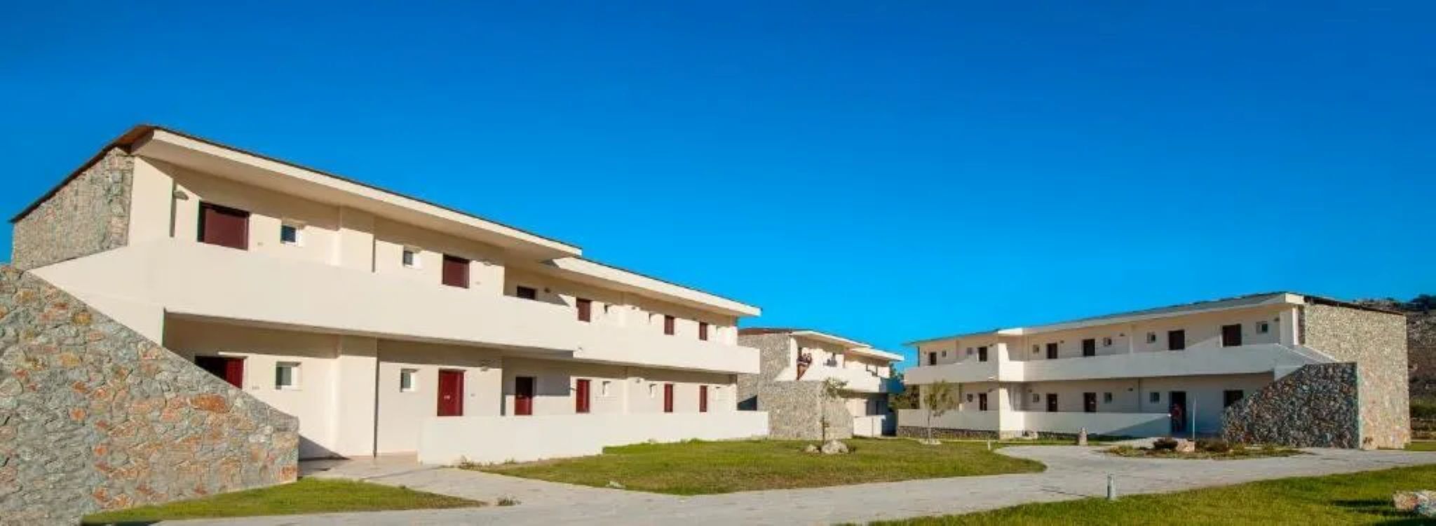 Een modern gebouw met een plat dak, meerdere ramen en een gevel van natuursteen.