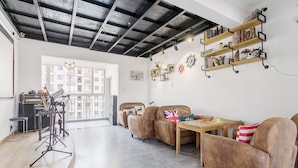 A spacious living area with leather sofas, a wooden coffee table, and a balcony with a view of buildings. - Le Tu Community (Kunming)