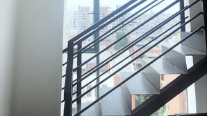 A staircase with metal railings leading to a landing with three wall-mounted paintings of animals. - Le Tu Community (Kunming)