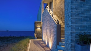 A modern building with a brick exterior, a staircase, and a view of the sea. - "Heimathafen 2" vacation apartment with sauna, south-facing terrace & roof terrace by the water (Olpenitz)