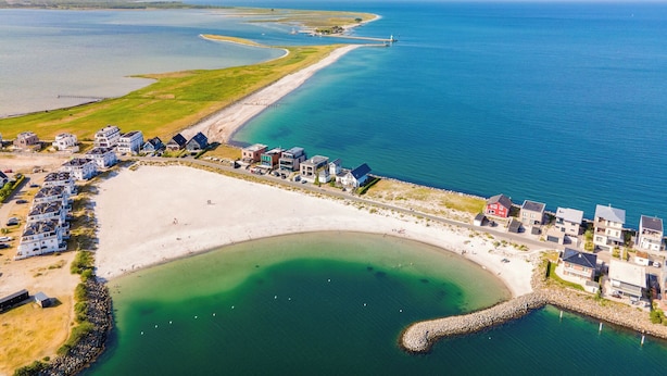 An aerial view of a coastal area with a beach, a marina, and residential buildings. - "Heimathafen 2" vacation apartment with sauna, south-facing terrace & roof terrace by the water (Olpenitz)