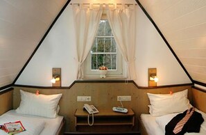 A triangular room with two beds, a window with curtains, bedside lamps, and a small table with a phone and remote control. - Apartment in Koblenz city forest (Koblenz)