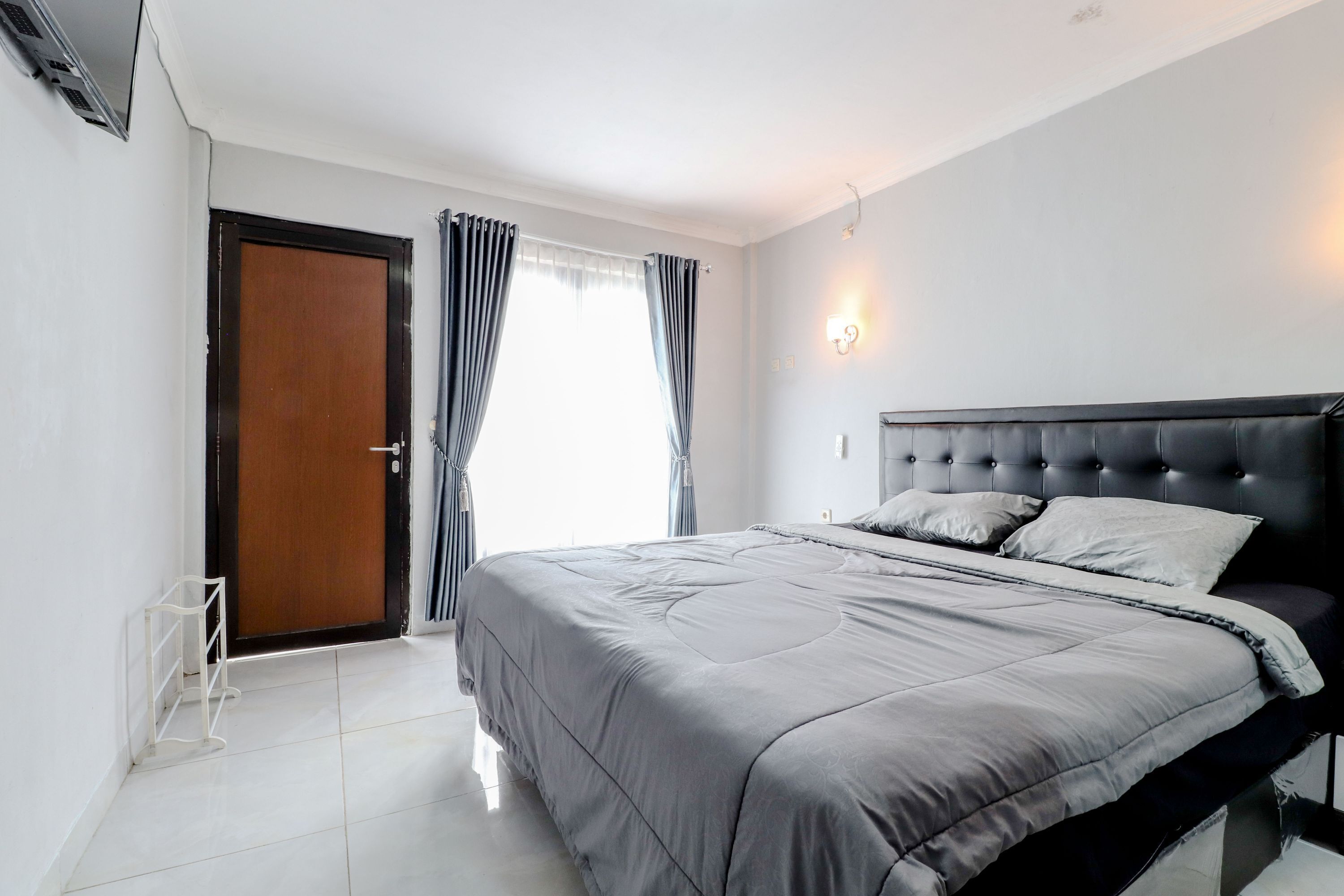 Une chambre avec un grand lit, une porte en bois et une fenêtre avec des rideaux.