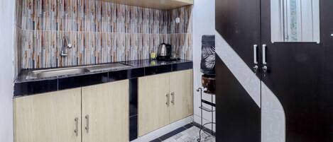 A kitchen with wooden cabinets, a black countertop, and a tiled backsplash.