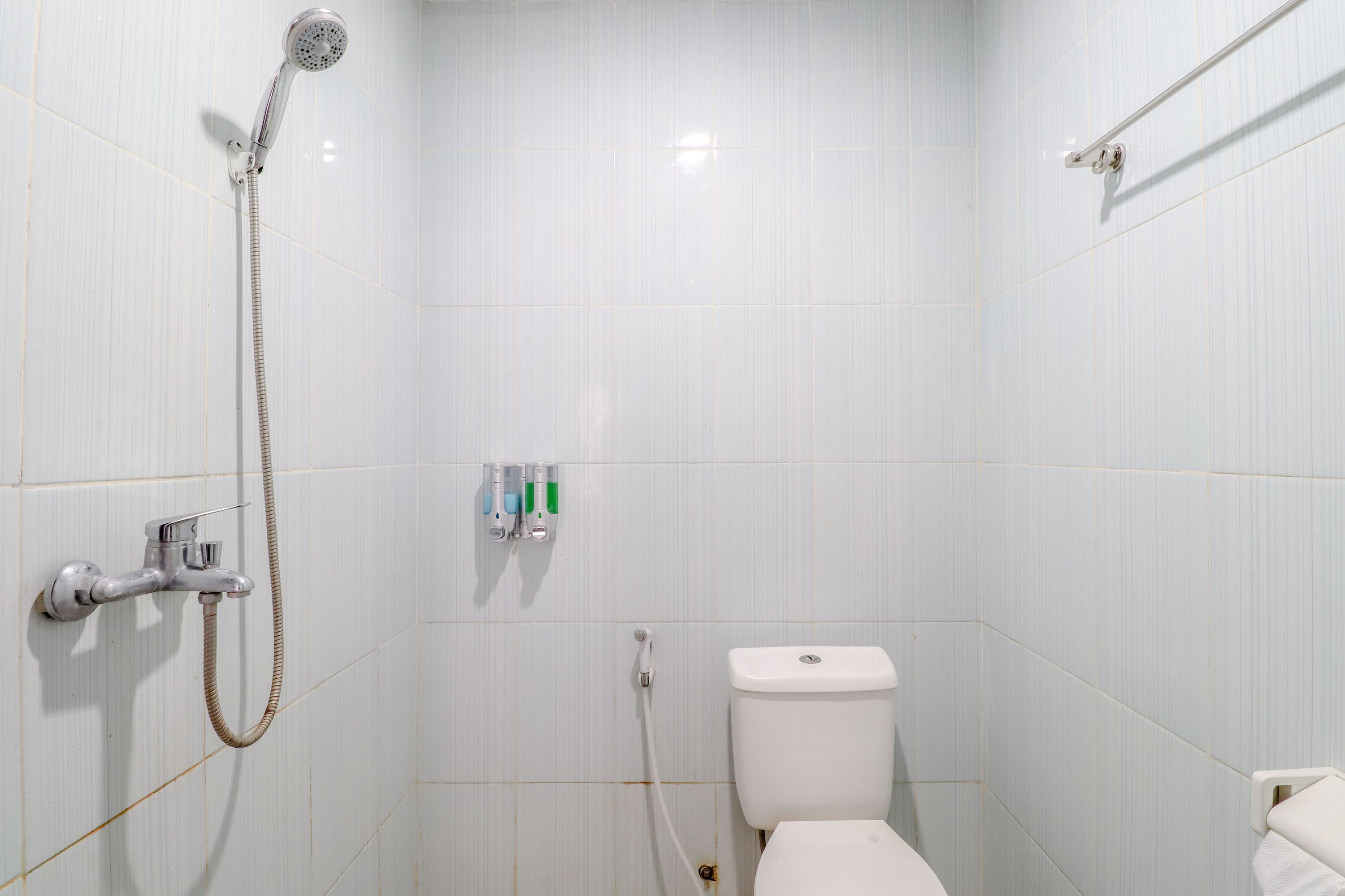 A small, white bathroom with a toilet, a shower, and a hand dryer.