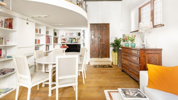 Ein modernes Interieur mit einer weißen Essecke, Holzschränken und einer Treppe zu einer oberen Ebene.