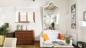 Ein Zimmer mit einem weißen Sofa, einem Holzschrank und einem Tisch mit Büchern und einer Blumenvase.