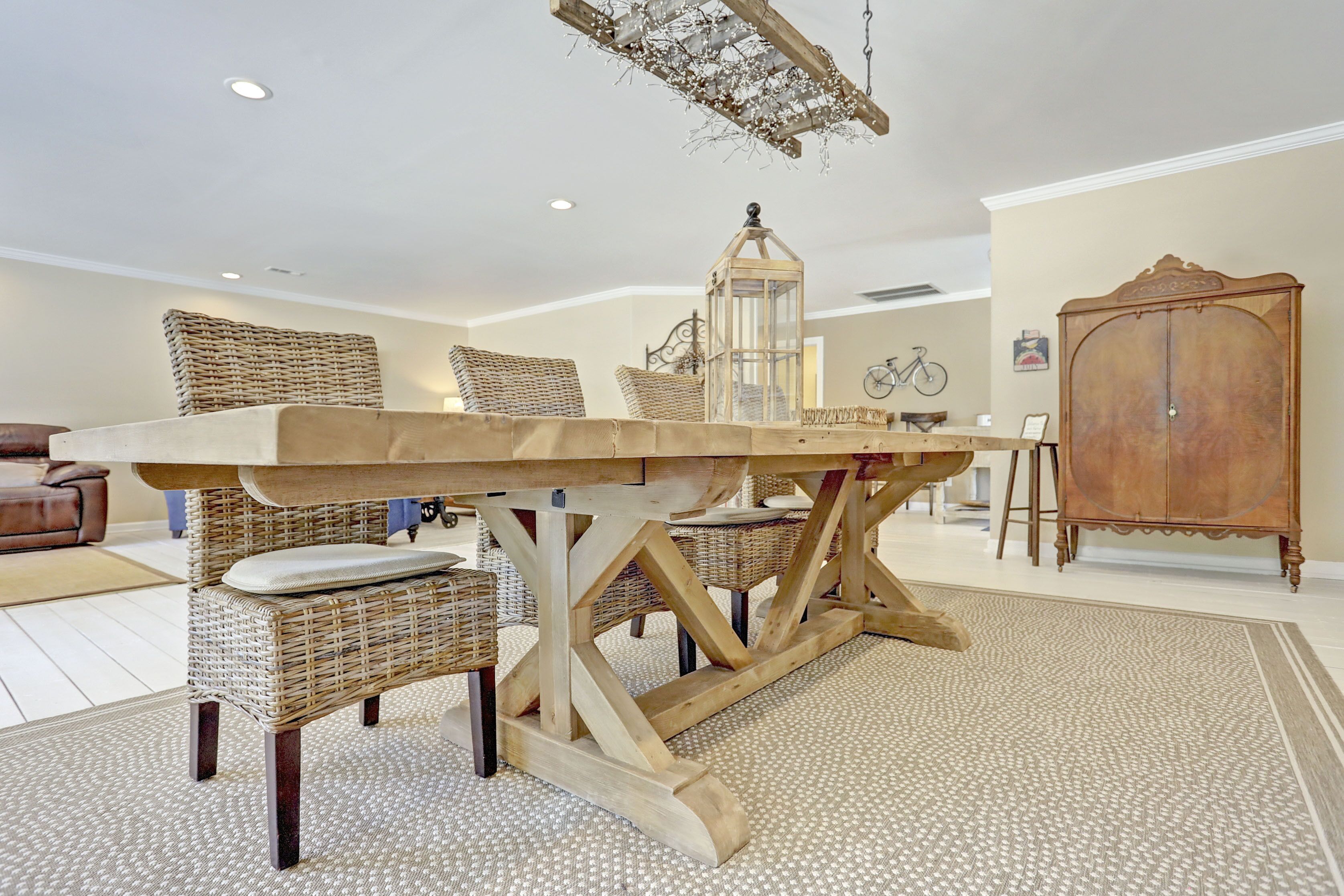 Un coin repas avec une table en bois, des chaises en osier, un lustre et un buffet d’époque.