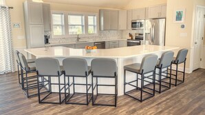 Una cocina moderna con una isla grande, taburetes de bar y electrodomésticos de acero inoxidable.