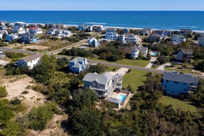 An aerial view of a coastal residential area with houses, roads, and a beach.