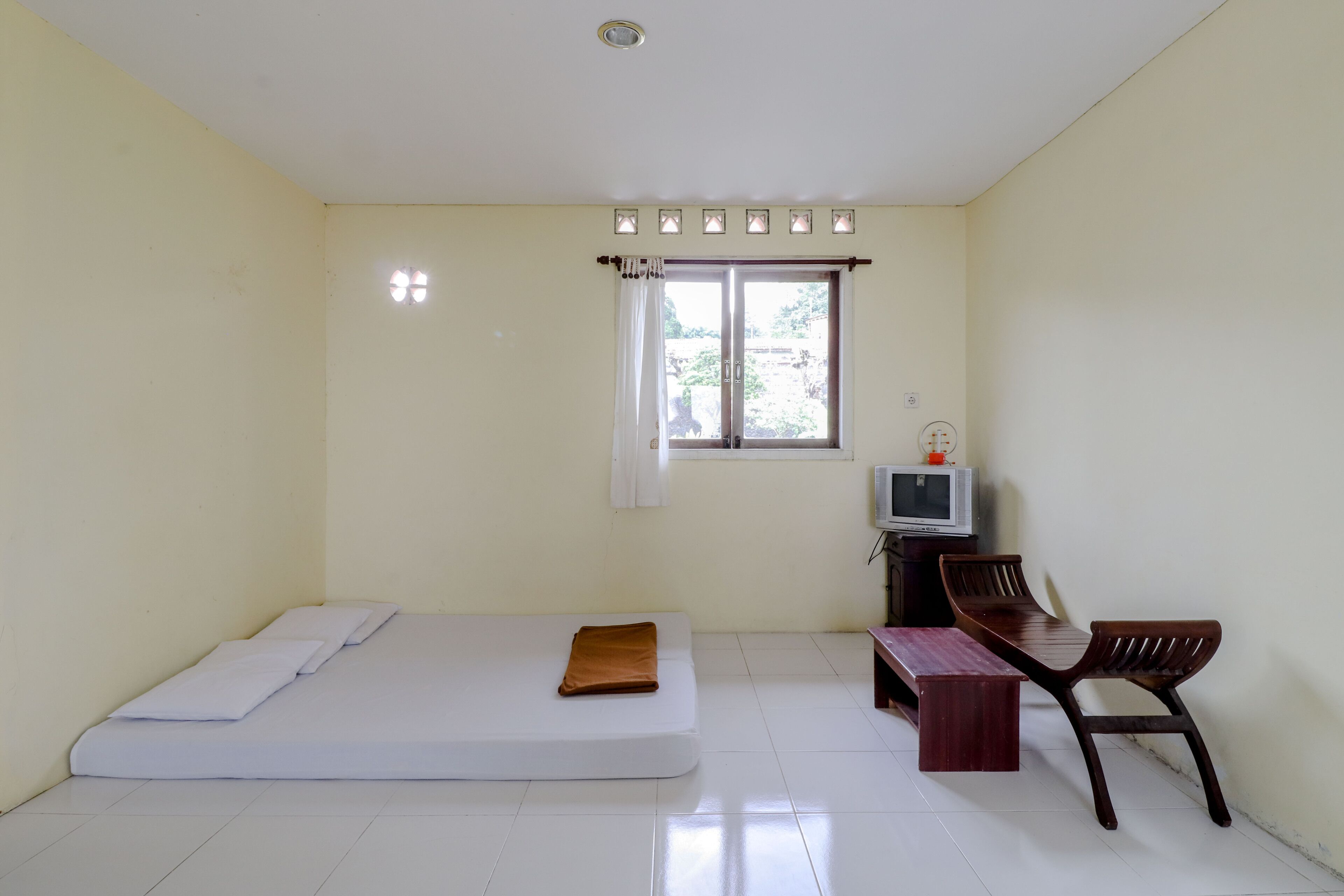 A room with a single bed, a small desk with a chair, and a window with curtains.